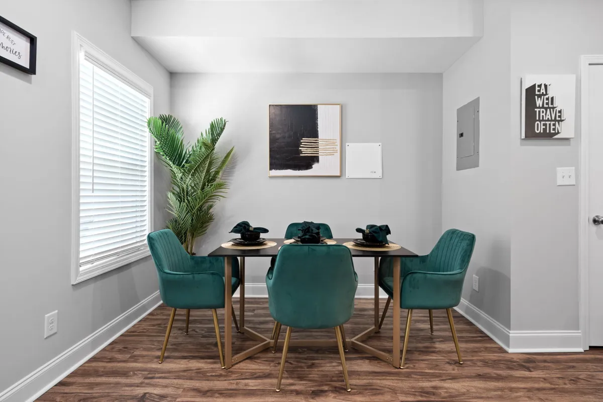 A welcoming dining nook is shown, featuring a dining table surrounded by comfortable chairs, vibrant artwork on the wall, and a touch of greenery. The arrangement encourages shared meals, conversations, and planning adventures, aligning with the section’s emphasis on connection and communal dining.