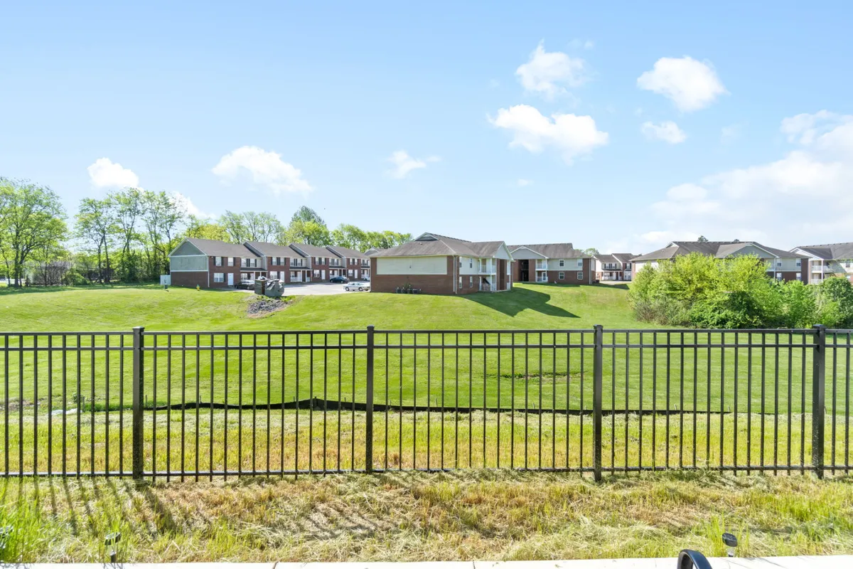 A tranquil, spacious green lawn with a fenced yard and residential buildings in the background. The open space is ideal for family picnics, outdoor games, or simply enjoying sunset moments together. The image captures the essence of outdoor family fun and provides a visual link to nearby parks like Dunbar Cave State Park.